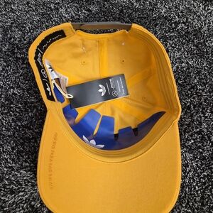 This cap is the Adidas x Bad Bunny x Mercedes-AMG F1 Racing Cap in gold.